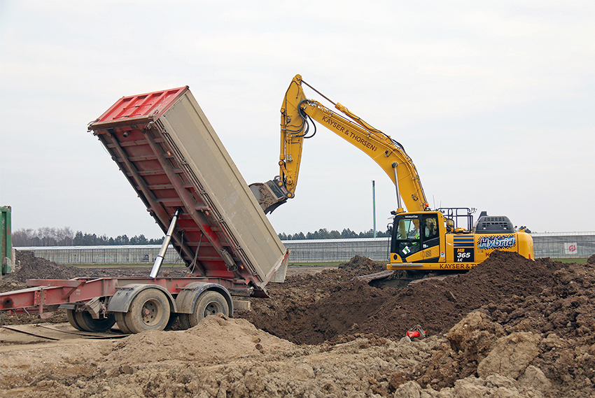 Der køres jord til et projekt ved Herfølge, og Komatsu-hybridgraveren sørger for både at få det hele ud af lastbilen og efterfølgende fordele det.